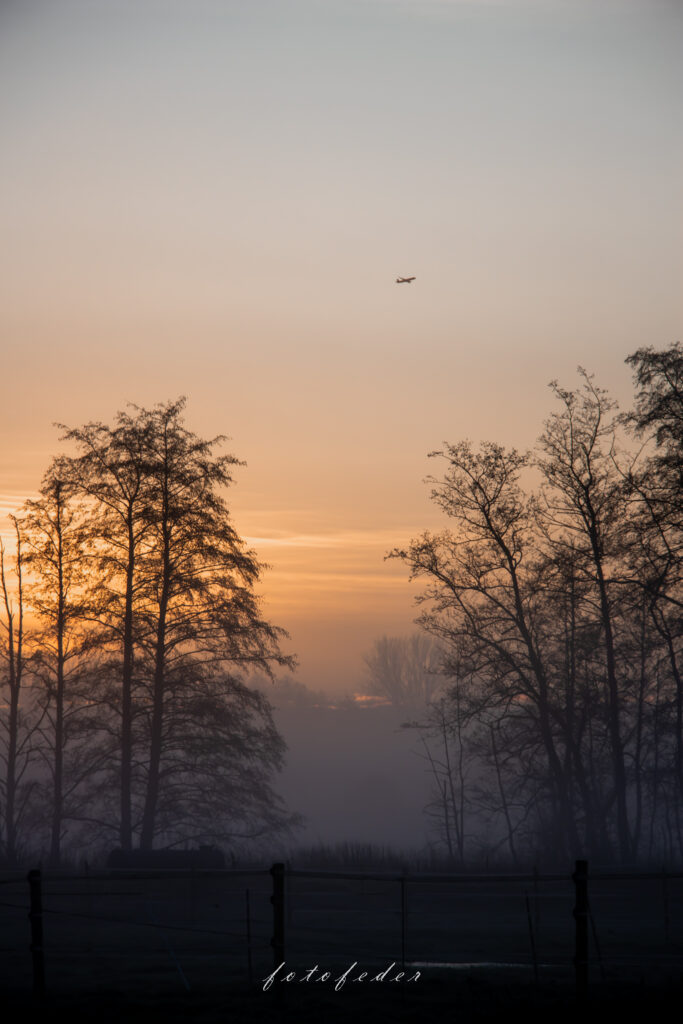 Landschaft bei Sonnenaufgang. Flugzeug fliegt über den Himmel bei Sonnenaufgang.