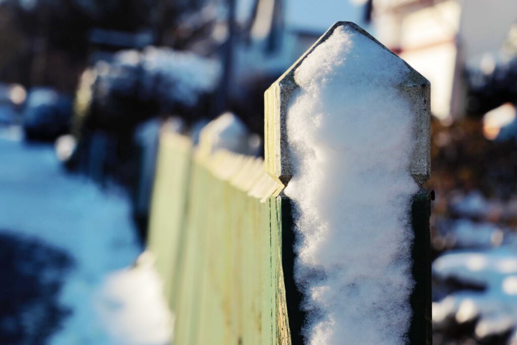Grüner Zaun von Schnee bedeckt